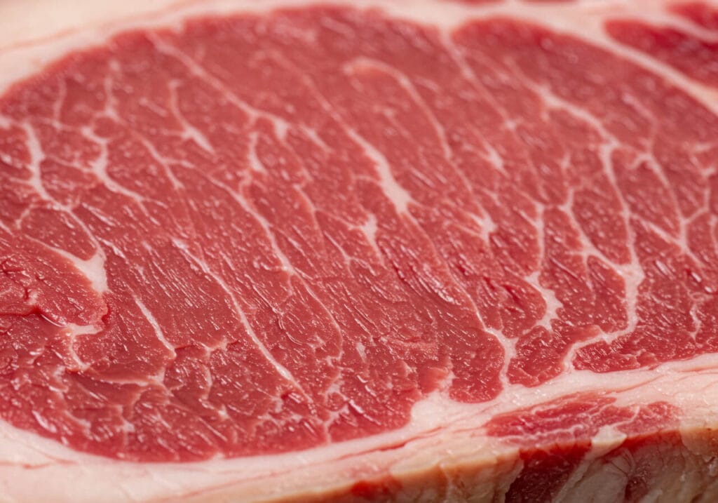 Gros plan du persillage d'un steak tomahawk montrant la riche distribution de gras dans une coupe Angus Certifié