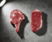 Ribeye vs strip steaks side by side on concrete surface showing marbling difference — Boucherie Beirut