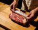 Boucher déballant un ribeye Wagyu Fullblood 9+ révélant un persillage extraordinaire sur un comptoir en bois – Boucherie Beirut Laval