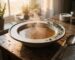 Steaming homemade beef bone broth in a ceramic bowl with thyme on a rustic wooden table – Boucherie Beirut Laval